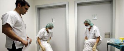 Dos auxiliares del Hospital La Fe (Valencia) se colocan los trajes de protección en presencia de un instructor.