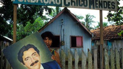 Un joven sostiene una pintura con el retrato de Chico Mendes, defensor de la Amazonía asesinado hace tres décadas.