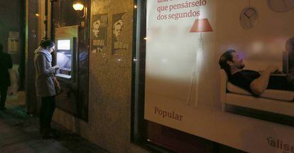 Una cliente utiliza un cajero de una oficina del Popular en Madrid.