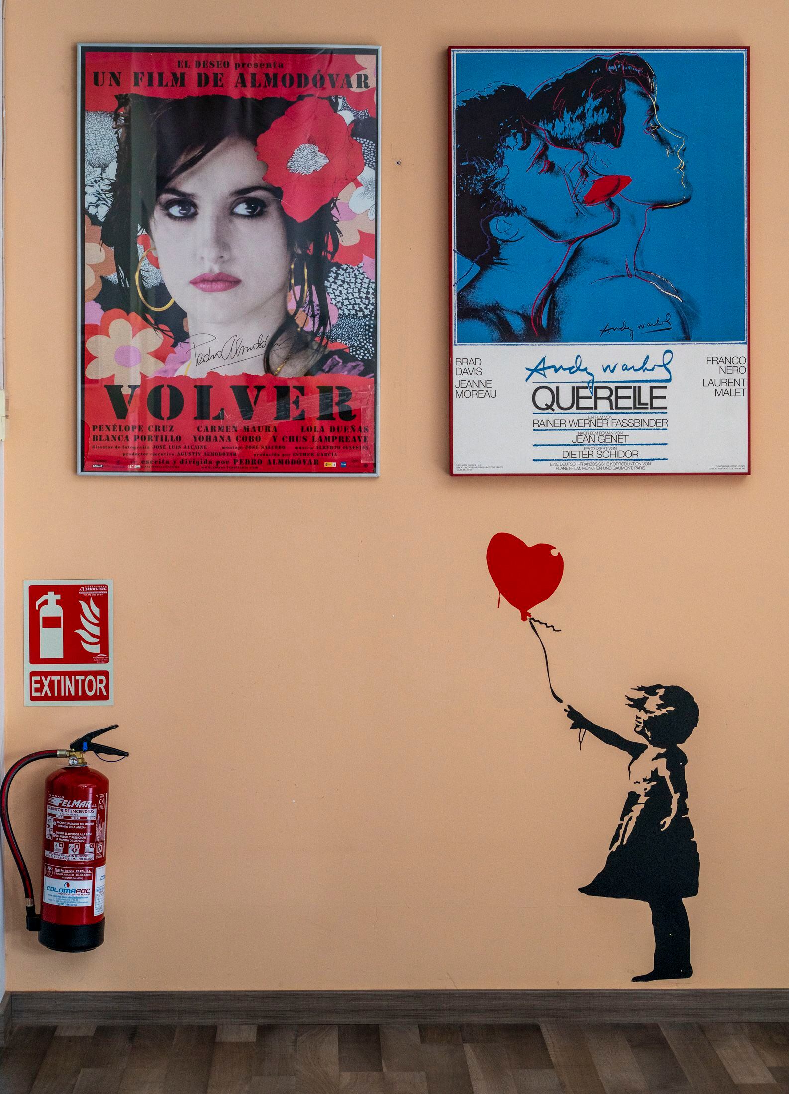 Una pared de la sede de Filmin con carteles de películas y el icónico dibujo de Banksy de la niña con el globo-corazón.