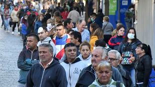 Cientos de pensionados y beneficiarios de planes sociales hacen fila frente a un banco de la ciudad argentina de Córdoba, este viernes.