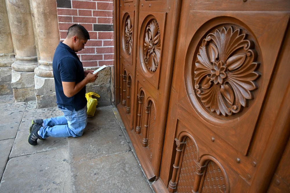Un hombre reza a las puertas de la Basílica del señor de los milagros en Colombia.