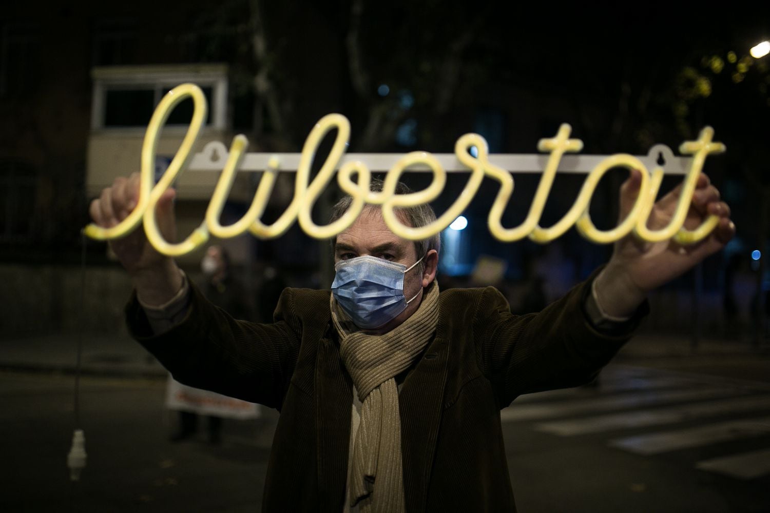 Una persona sostiene una pancarta luminosa frente a las puertas del centro penitenciario.