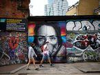 People wearing protective face masks walk past streetart in Shoreditch following the outbreak of the coronavirus disease (COVID-19), London, Britain, May 10, 2020. REUTERS/Henry Nicholls