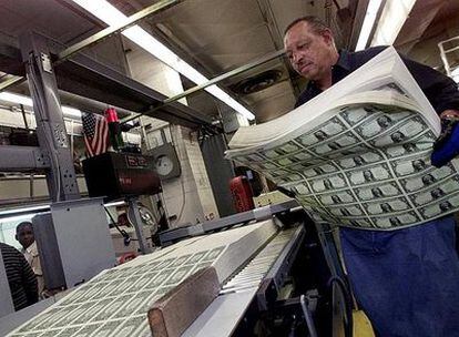Un empleado de la Oficina de Impresión y Grabado de la Moneda en Estados Unidos trabaja con un grupo de billetes de un dólar.