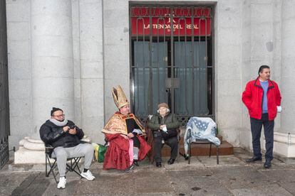 Los primeros asistentes a la ceremonia del sorteo de la Lotería de Navidad en el Teatro Real de Madrid hacen cola dos días antes de que se celebre.