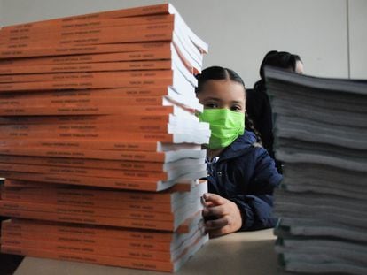 En agosto de 2022, una niña se asoma detrás de una torre de libros de texto de la SEP, en una primaria de la Ciudad de México.