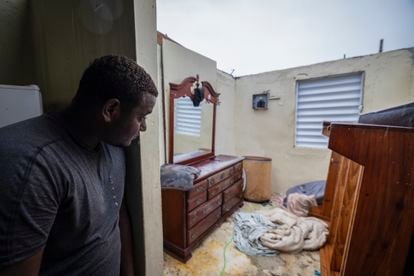 Nelson Cirino mira los daños causados en su vivienda tras el paso del huracán Fiona en Loiza, este domingo. 