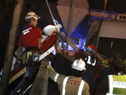 Els bombers mouen el cos d'un home arrossegat per la corrent.