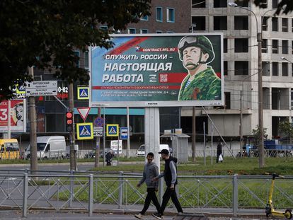 Dos hombres pasan este jueves, en San Petersburgo, frente a un cartel que dice "Servir a Rusia es un trabajo real".