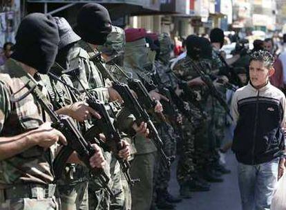 Un joven palestino pasa delante de milicianos de Al Fatah desplegados en  la ciudad de Ramala, en Cisjordania.