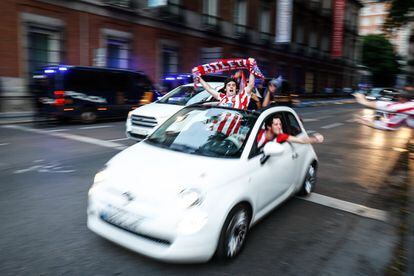 Aficionados del Atlético de Madrid celebran desde el coche mientras pasan por la Plaza de Neptuno la victoria del título de liga de su equipo. 
