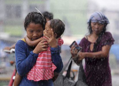 Varias personas caminan bajo la lluvia por la devastada ciudad de Tacloban.