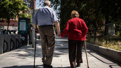 Un hombre y una mujer mayores caminan por la calle Caramuel, en el barrio de Puerta del Angel, Madrid.