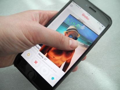 Un usuario sostiene un teléfono inteligente que muestra la aplicación Tinder.