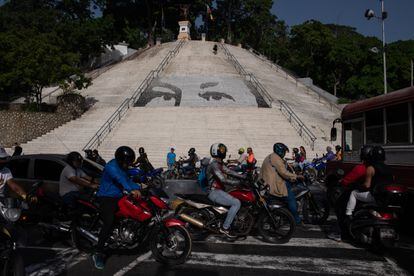 Los ojos de Hugo Chávez solían mirar a Venezuela desde aparentemente todas partes: los techos de las oficinas gubernamentales, los muros de las viviendas, incluso desde parques y espacios públicos. En la imagen, motociclistas pasan frente a una escalera con un mural que representa los ojos del difunto presidente venezolano Hugo Chávez en el Parque Calvario en Caracas, el 7 de junio de 2022.