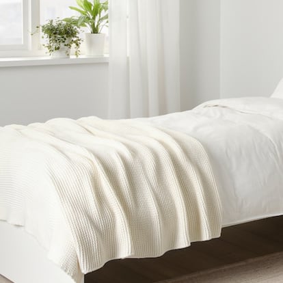 Cama con una funda nórdica y una manta ligera ideales para el verano.