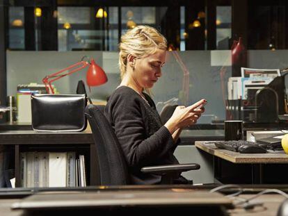 Una mujer consulta su teléfono en el trabajo.