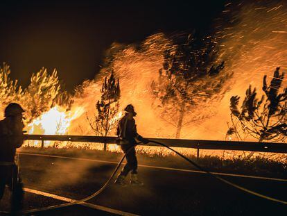 Operarios de las Brigadas de Refuerzo de Incendios Forestales (BRIF) luchan contra las llamas en la madrugada de este sábado para extinguir el incendio declarado en el día anterior en la parroquia de Boiro.
