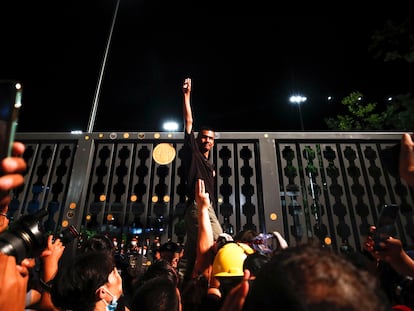 Un activista prodemocracia saluda con tres dedos en alto a los medios a las puertas del Parlamento tailandés en Bangkok este jueves