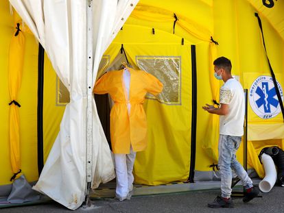 Un sanitario y un paciente entran en el hospital de campaña instalado ante el CUAP Prat de la Riba de Lleida, este jueves.