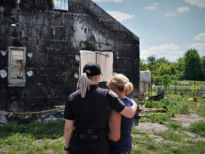 La agente Olga Yuskevich trata de consolar a Liubov, una cocinera de 60 años, delante de los restos de su casa