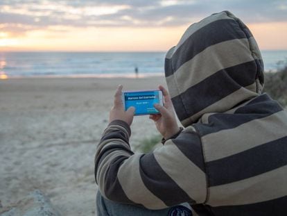 Un menor juega con su móvil a la aplicación  “Narcos del Estrecho” en una de las playa de Cádiz. 