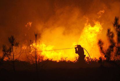 Un bombero apunta con una manguera sobre las llamas en Covelo, el 17 de octubre.