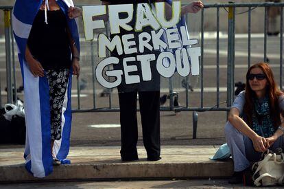 Manifestantes portan una pancarta que pida que Merkel se vaya.