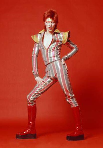 Bowie como Ziggy Stardust, con traje estravagantee y botas de plataforma y charol.