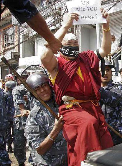 Un monje tibetano sostiene un cartel ("ONU, ¿estás ahí?") cuando es arrestado ayer en Katmandú.