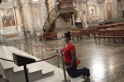 Una mujer reza con una mascarilla puesta en la catedral de Santiago de Chile.