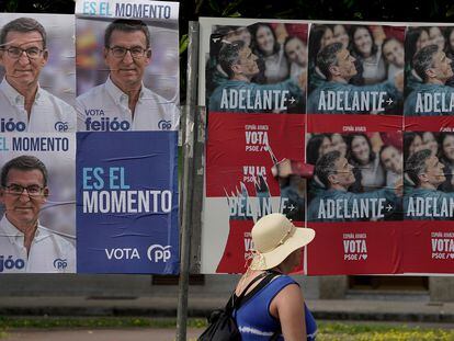 Una mujer pasa frente a carteles electorales del PP y PSOE en Gijón.