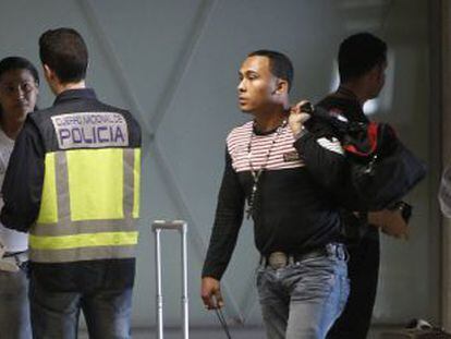 Un polic&iacute;a con viajeros llegados al aeropuerto de Barajas. 