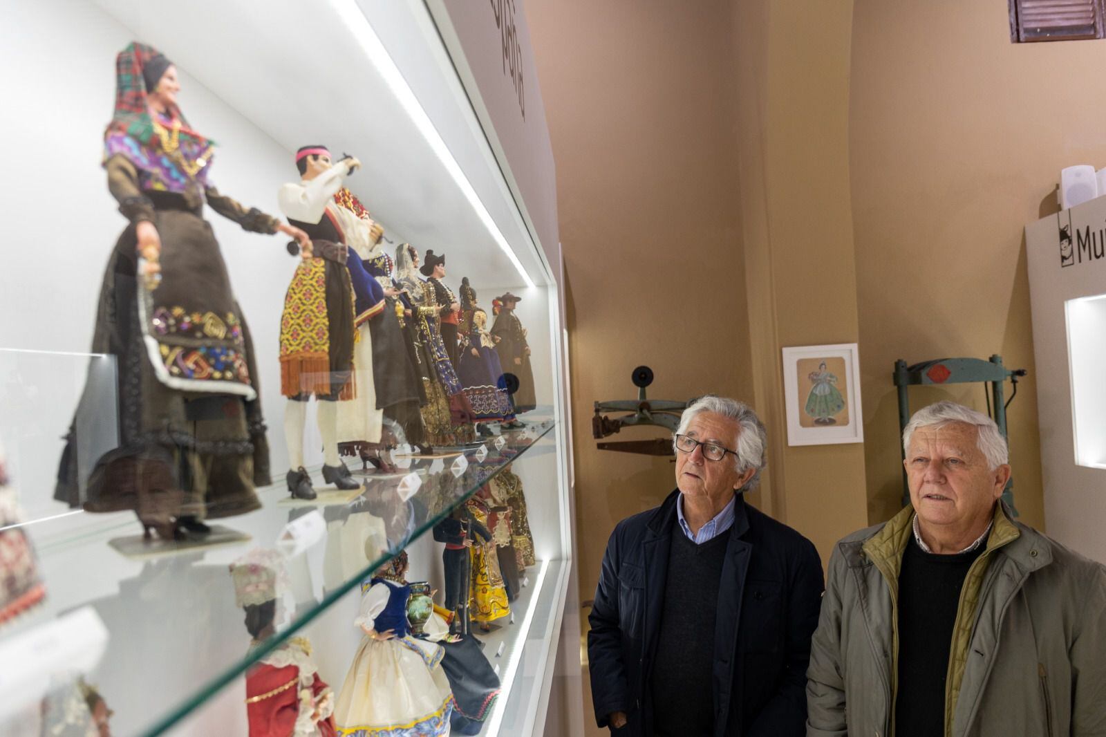 Antonio y Ernesto Marín, hijos del creador de Muñecas Marín, contemplan algunas de las creaciones de la empresa Muñecas Marín que se exponen en Chiclana.