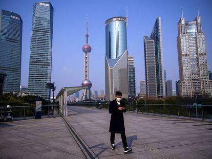 Un hombre con mascarilla pasa por el distrito financiero de Lujiazui en Pudong (Shanghái). 