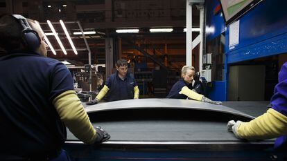 Varios trabajadores pulen manualmente el capó de un coche en la fábrica de Gestamp en Dueñas (Palencia).