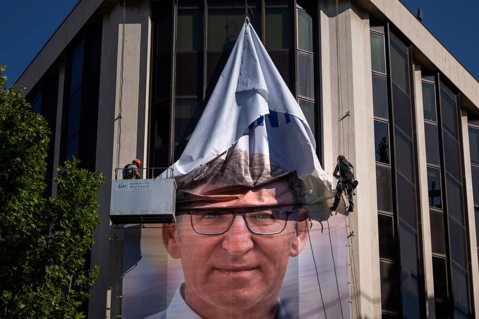 Retirada de uno de los carteles electorales del PP en su sede de Génova.