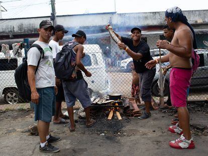 Un grupo de venzolanos asa pescado en una calle aledaña a la estación de autobuses de Manaos (Brasil).