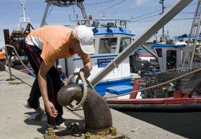 Un pescador amarra su barco en un puerto de Andalucía