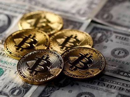 Monedas simuladas de Bitcoin sobre billetes de d&oacute;lar.