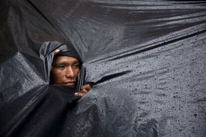 Un indígena Mbyá Guaraní se protege de la lluvia.