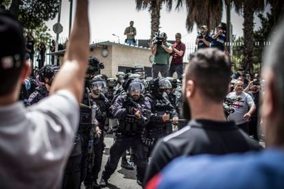 Un agente de fronteras de la policía israelí apunta con su arma a los asistentes al cortejo fúnebre a la salida del hospital San José, en Jerusalén. 