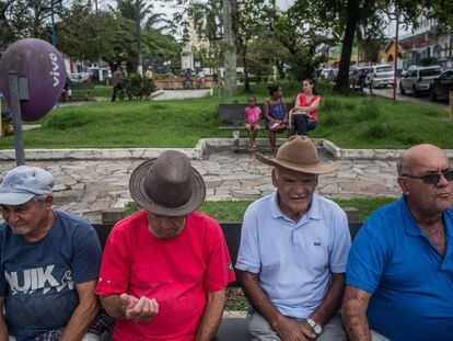 Cuatro hombres descansan en la plaza central de Eldorado delante de dos mujeres y una niña.