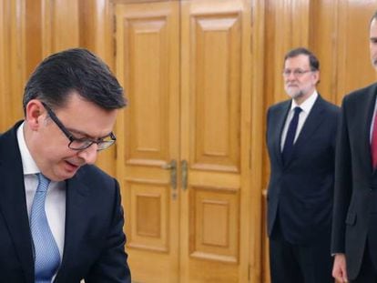 El nuevo ministro de Economía, Román Escolano (izquierda), jura su cargo ante el Rey Felipe VI (derecha) en el Palacio de la Zarzuela de Madrid, en presencia del presidente del Gobierno, Mariano Rajoy.