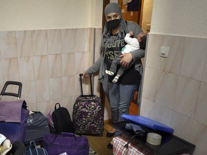 La madre lleva en brazos a Amir, de un mes, mientras acaba de sacar al descansillo los últimos bultos que se llevan.