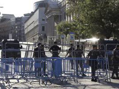 Agentes de la Policía tras las vallas colocadas para impedir el acceso a la zona del Congreso. Varios centenares de funcionarios han iniciado una manifestación esta tarde en las inmediaciones del Palacio de las Cortes, blindado por la Policía, en protesta por los últimos recortes del Gobierno.