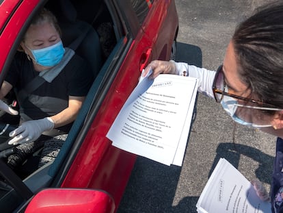 Una representante del Ayuntamiento de Hialeah, Florida, reparte documentos para solicitar los beneficios por desempleo.
