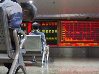 Dos inversores, este lunes, frente a un panel de cotizaciones en Pekín (China).