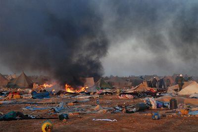 Entre jaimas destruidas o en llamas, varios uniformados marroquíes recorren tras el ataque el campamento saharaui de Agdaym Izik.